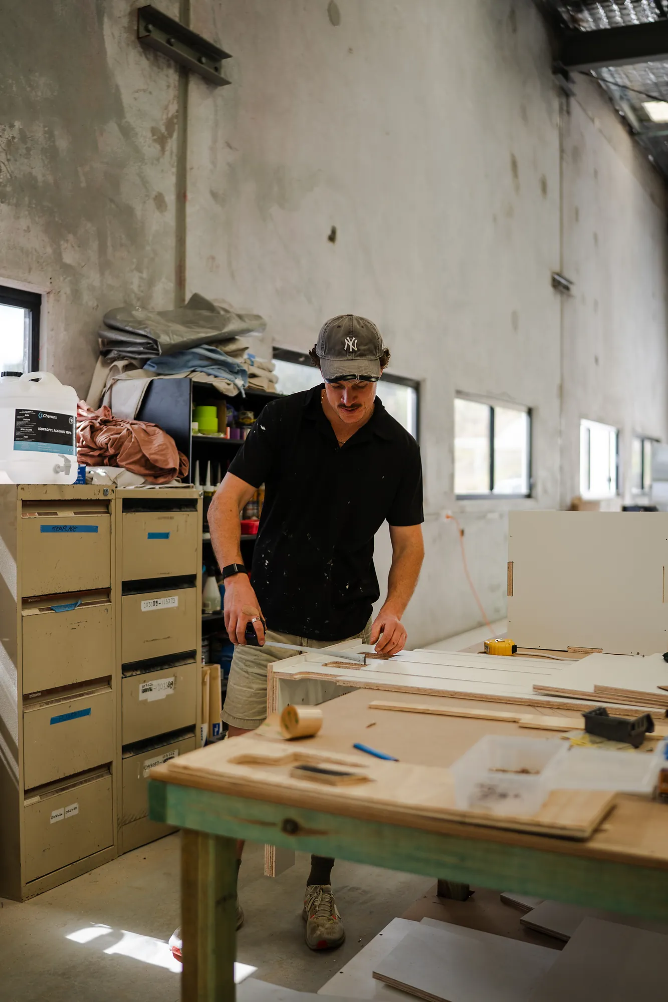 Builder assembling numbered CNC plywood parts of the campervan kit at the workshop bench
