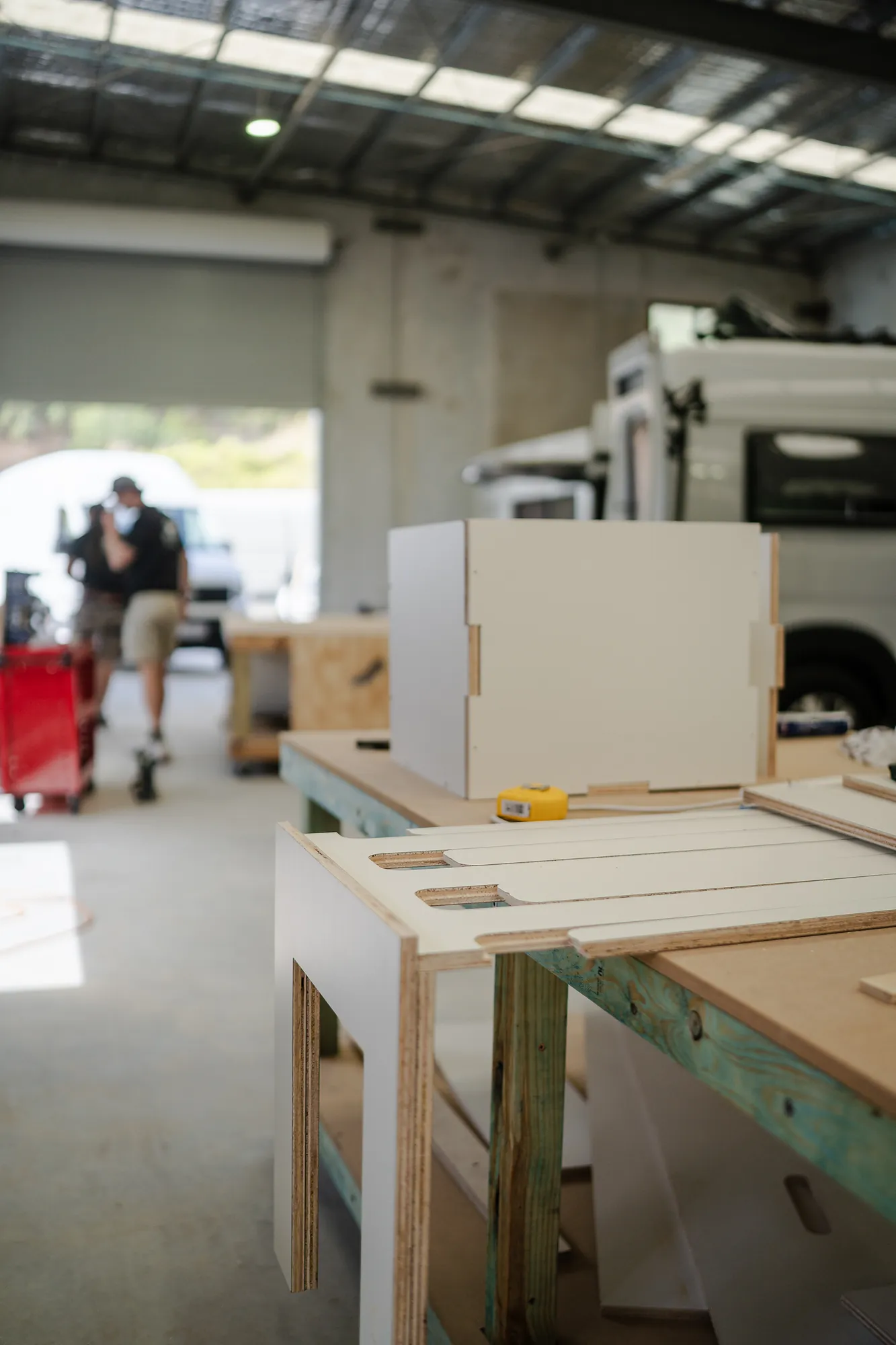 Flat-pack CNC-cut plywood parts stacked on the workshop bench, ready for assembly